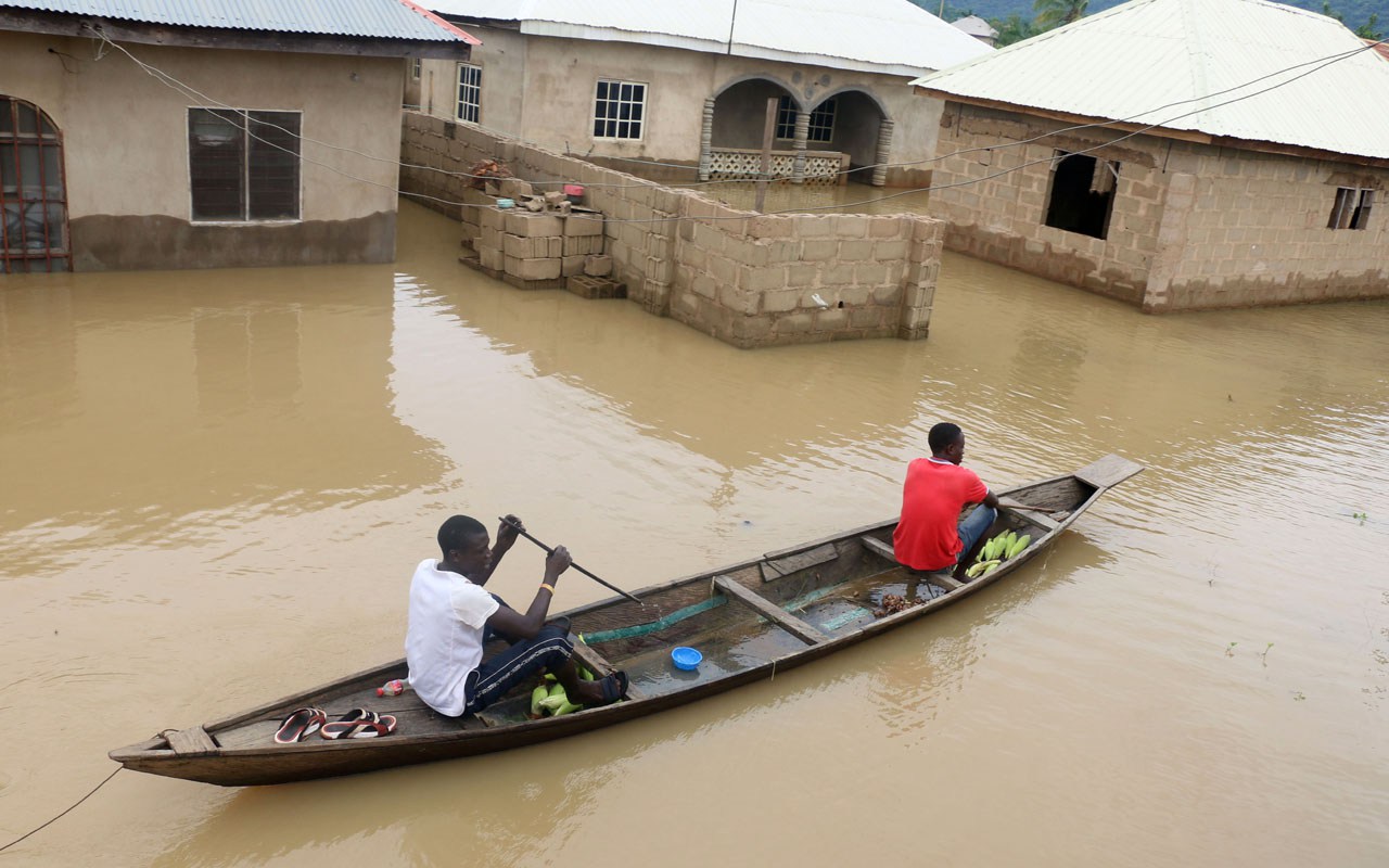 Residents steer canoe past flooded houses following heavy rain
