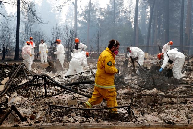 A volunteer search and rescue team comb a home destroyed by the California wildfire in Paradise. Reuters Photo